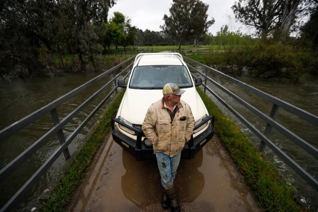 Andrew Watson watches on as water flows beneath a bridge on his Bungowannah farm at a rapid rate. Picture by James Wiltshire